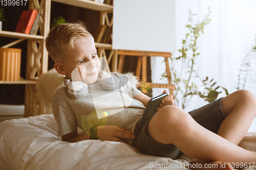 Image of Little boy using different gadgets at home