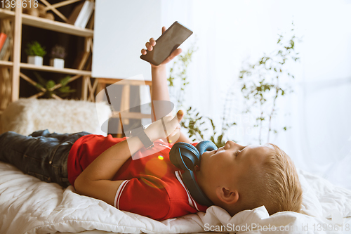 Image of Little boy using different gadgets at home