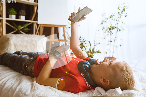 Image of Little boy using different gadgets at home