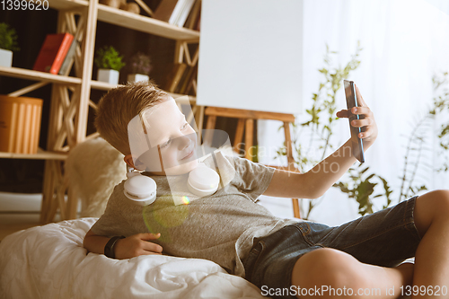 Image of Little boy using different gadgets at home