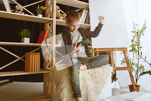 Image of Little boy using different gadgets at home