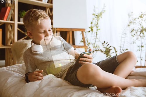 Image of Little boy using different gadgets at home