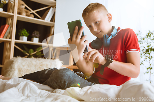 Image of Little boy using different gadgets at home