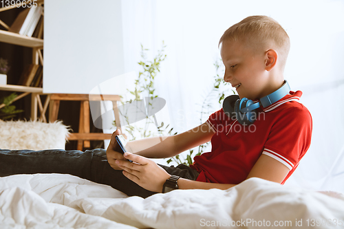 Image of Little boy using different gadgets at home