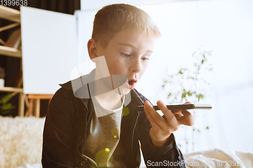 Image of Little boy using different gadgets at home