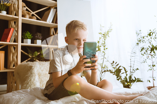 Image of Little boy using different gadgets at home