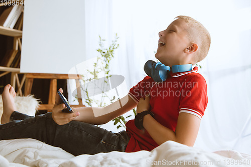 Image of Little boy using different gadgets at home