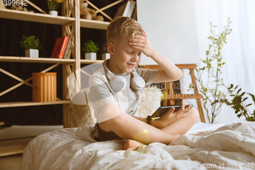 Image of Little boy using different gadgets at home