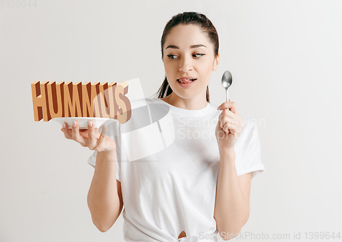 Image of Food concept. Model holding a plate with letters of Hummus