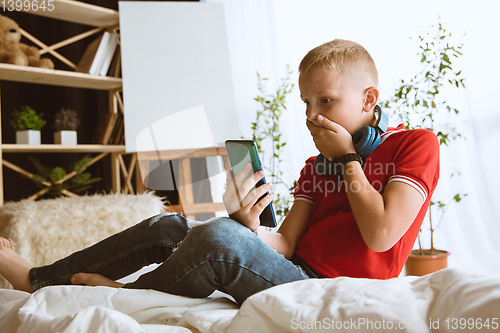 Image of Little boy using different gadgets at home