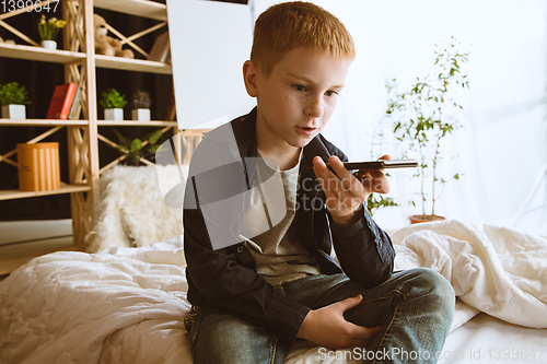 Image of Little boy using different gadgets at home