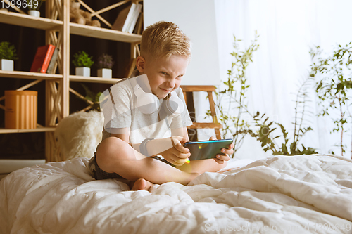 Image of Little boy using different gadgets at home