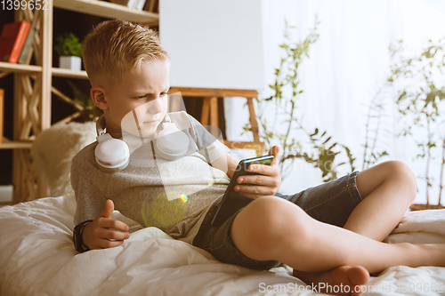 Image of Little boy using different gadgets at home