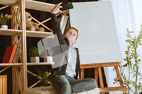 Image of Little boy using different gadgets at home