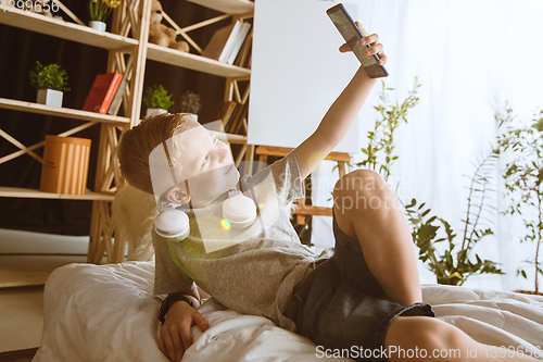 Image of Little boy using different gadgets at home