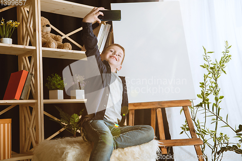Image of Little boy using different gadgets at home