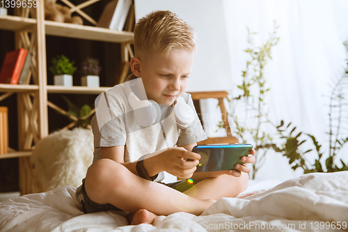 Image of Little boy using different gadgets at home