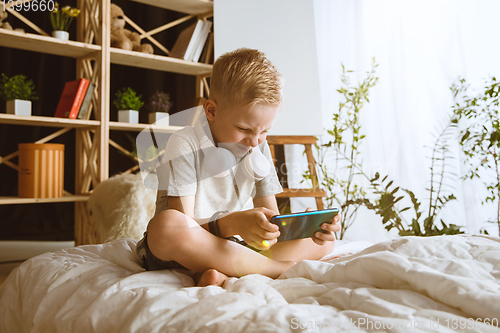 Image of Little boy using different gadgets at home