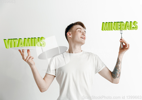 Image of Food concept. Model holding a plate with letters of Vitamins, Minerals