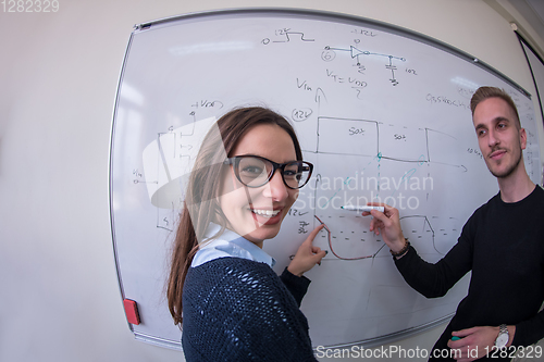 Image of students writing on the white chalkboard