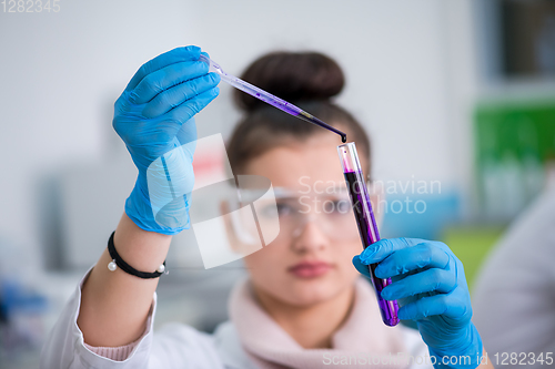 Image of female student with protective glasses making chemistry experime