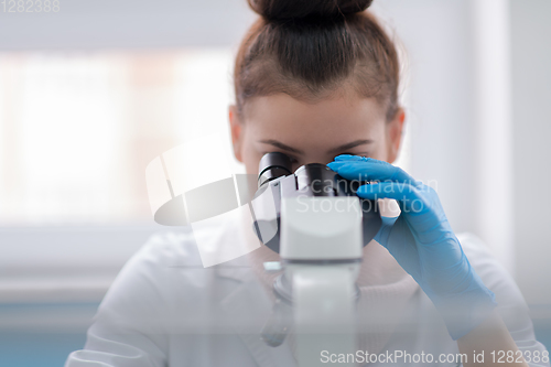 Image of female student scientist looking through a microscope