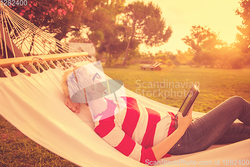 Image of woman using a tablet computer while relaxing on hammock