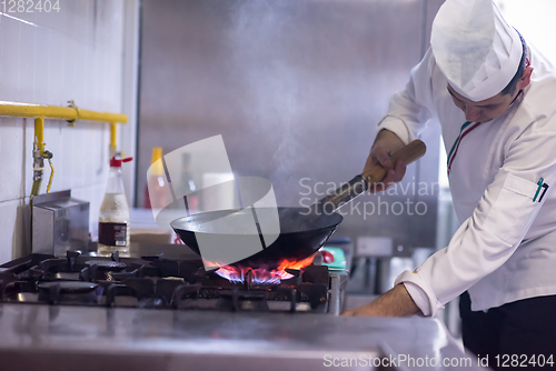 Image of chef preparing food, frying in wok pan