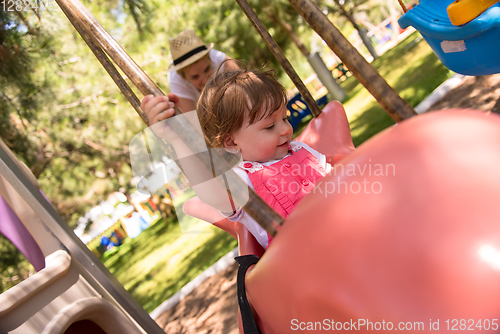 Image of mother and daughter swinging in the park