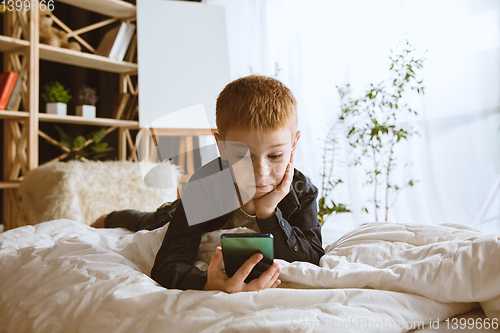 Image of Little boy using different gadgets at home