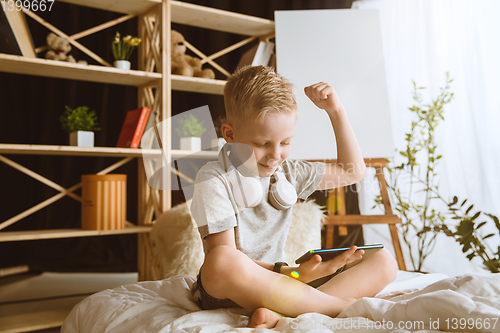 Image of Little boy using different gadgets at home