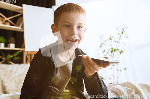 Image of Little boy using different gadgets at home