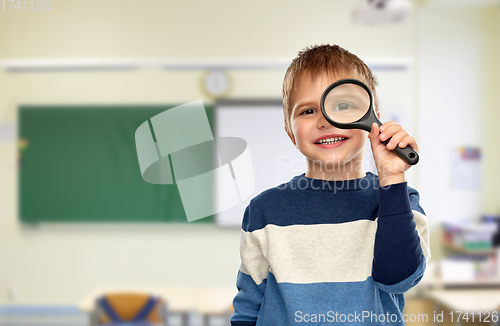 Image of boy looking through magnifying glass at school