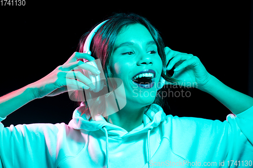 Image of woman in headphones listening to music in neon