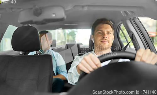 Image of male driver with wireless earphones driving car