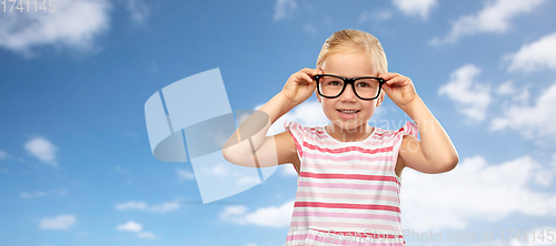 Image of smiling little girl in glasses over sky background