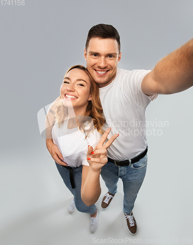 Image of happy couple in white t-shirts taking selfie