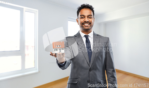 Image of indian man realtor with house model at new home