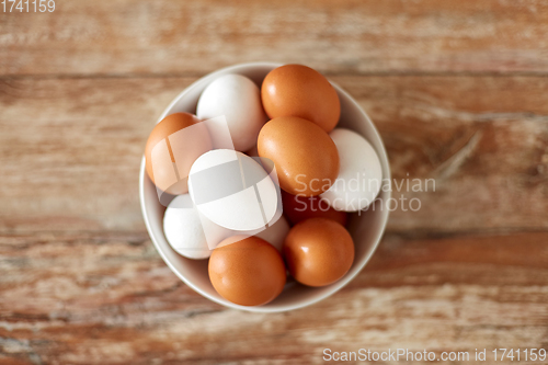 Image of close up of eggs in ceramic bowl on wooden table