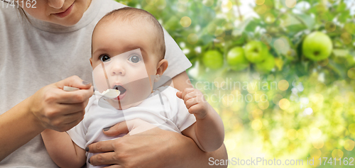 Image of close up of mother with spoon feeding little baby