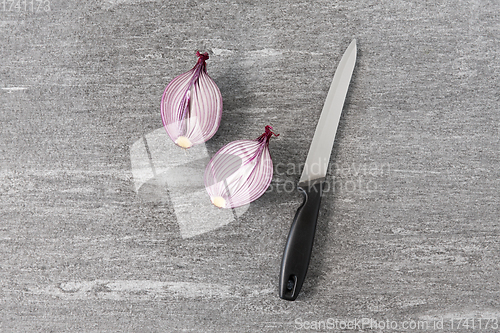 Image of cut red onion and knife on slate stone background