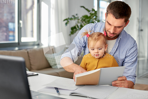 Image of working father with baby daughter at home office