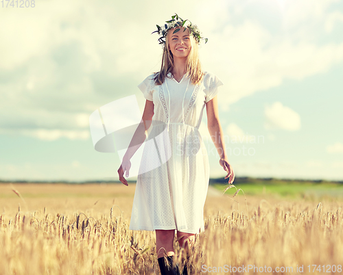 Image of happy young woman in flower wreath on cereal field