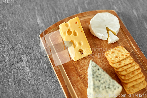 Image of different cheeses and crackers on wooden board