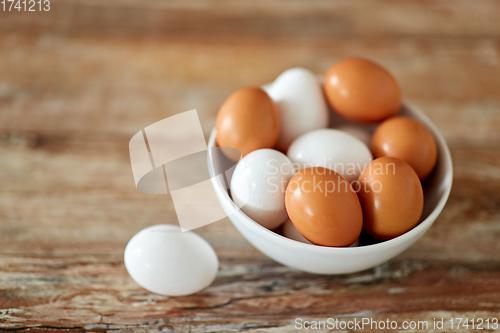 Image of close up of eggs in ceramic bowl on wooden table