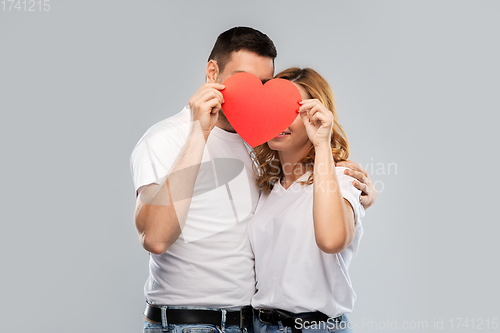 Image of smiling couple hiding behind big red heart