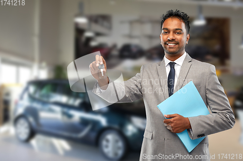 Image of happy indian car dealer with car key at showroom