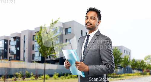 Image of indian man realtor with folder on city street