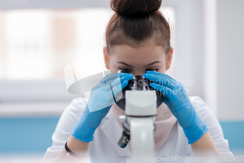 Image of female student scientist looking through a microscope