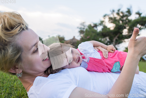 Image of mother and little daughter playing at backyard